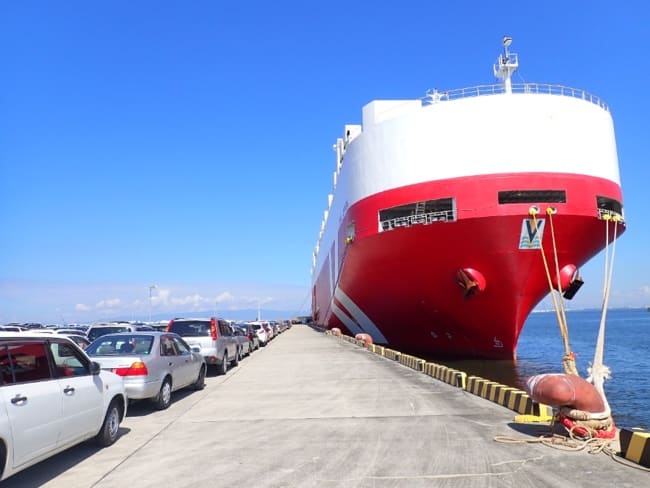Cars lined up on the quay beside a roll-on/roll-off car carrier